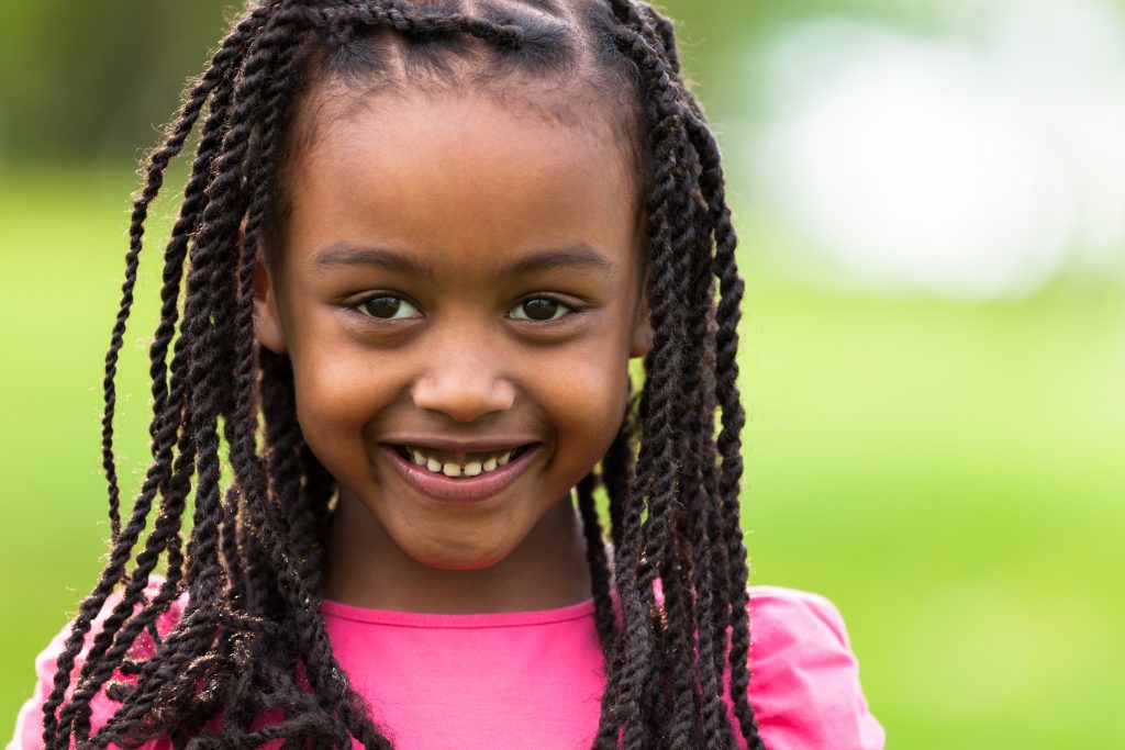 Outdoor close up portrait of a cute young black girl smiling