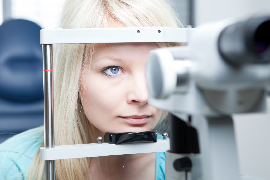 pretty young woman having her eyes examined by an eye doctor on a slit lamp
